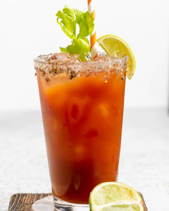 Red snapper cocktail with pepper celery salt rim garnished with celery and a lime wedge.