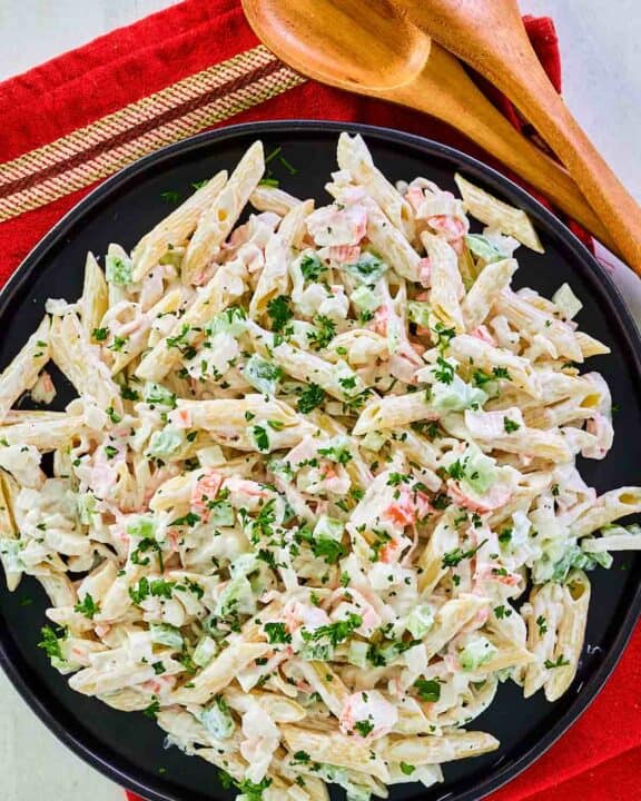 Overhead view of seafood pasta salad on a black plate.
