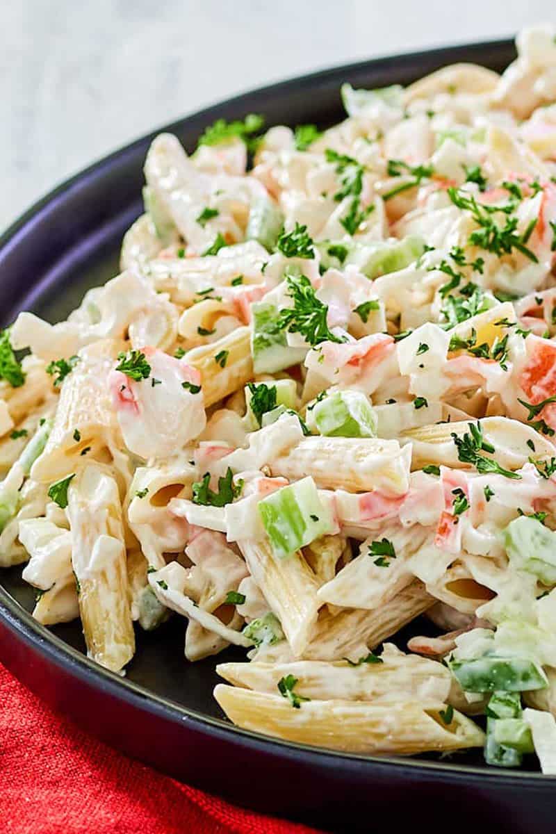 Closeup of seafood pasta salad on a black plate.