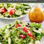 Traditional Greek salad and a small pitcher of dressing next to it.