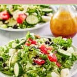 Traditional Greek salad on a large plate and the dressing in a small pitcher.