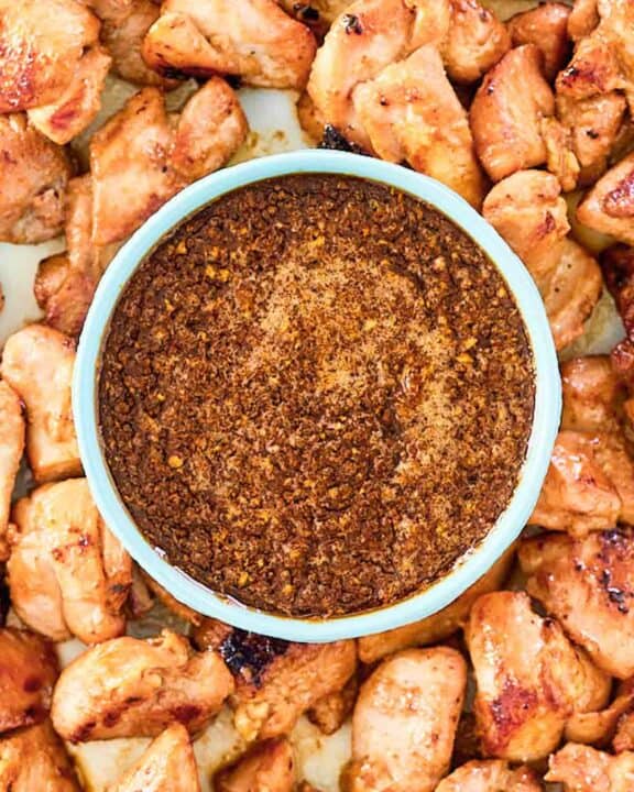 Overhead view of copycat Benihana ginger sauce in a bowl with cooked chicken pieces around it.