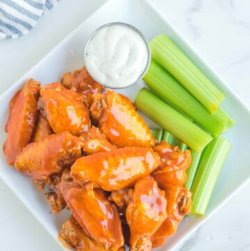 Overhead view of copycat Buffalo Wild Wings Buffalo wings, dipping sauce, and celery on a plate.