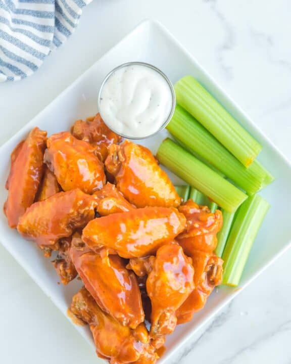 Overhead view of copycat Buffalo Wild Wings Buffalo wings, dipping sauce, and celery on a plate.