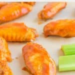 Homemade Buffalo Wild Wings Buffalo wings scattered on parchment paper.