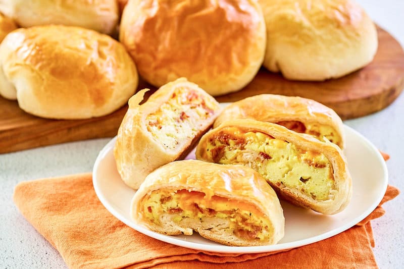 Copycat Dunkin stuffed biscuit bites with bacon on a plate and a wooden board.