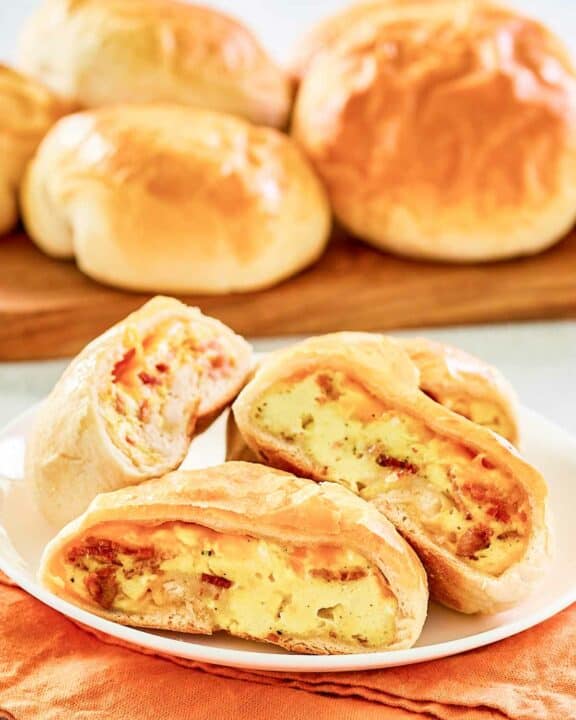 Copycat Dunkin stuffed biscuit bites with bacon on a wooden board and a plate.