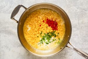 Corn, jalapeno peppers, and pimento peppers in a pan.