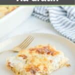 Potato au gratin serving and a fork on a white plate.