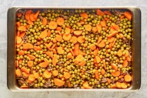 Peas and carrots in a baking pan.