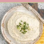 Overhead view of homemade boursin cheese spread and a knife on a plate.