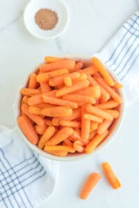 Overhead view of copycat Cracker Barrel baby carrots and a small bowl of ground nutmeg.