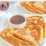 Homemade Cracker Barrel French toast and a bowl of syrup on a plate.