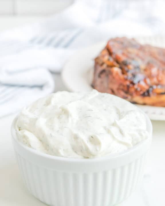 Copycat Outback tiger dill sauce in a bowl with a steak on a plate behind it.