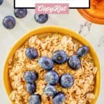 Overhead view of overnight oats in a bowl topped with fresh blueberries and honey.