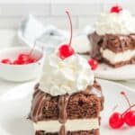 Homemade Shoney's hot fudge cake and maraschino cherries on a plate.