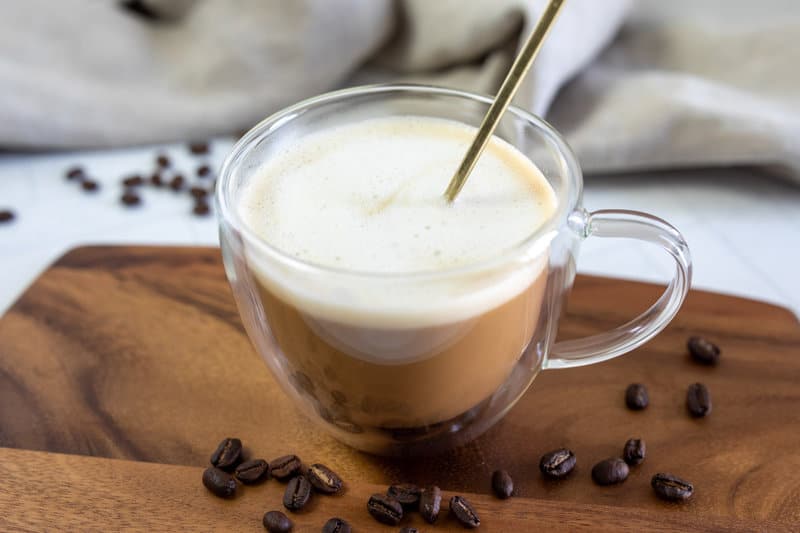 Copycat Starbucks oleato caffe latte and a spoon in a clear insulated mug.