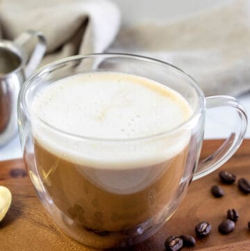 Copycat Starbucks Oleato caffe latte and coffee beans on a wood board.