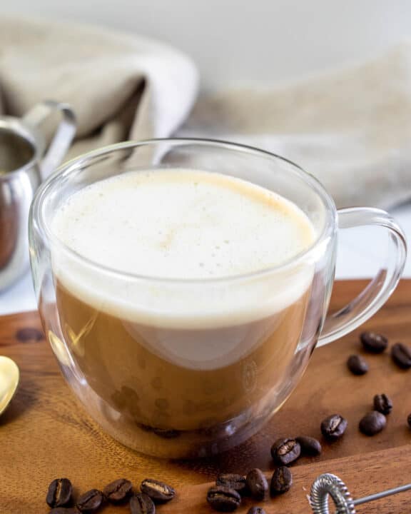 Copycat Starbucks Oleato caffe latte and coffee beans on a wood board.
