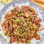 Overhead view of teriyaki beef stir fry over rice on a plate.
