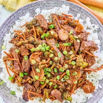 Overhead view of teriyaki beef stir fry over rice on a plate.