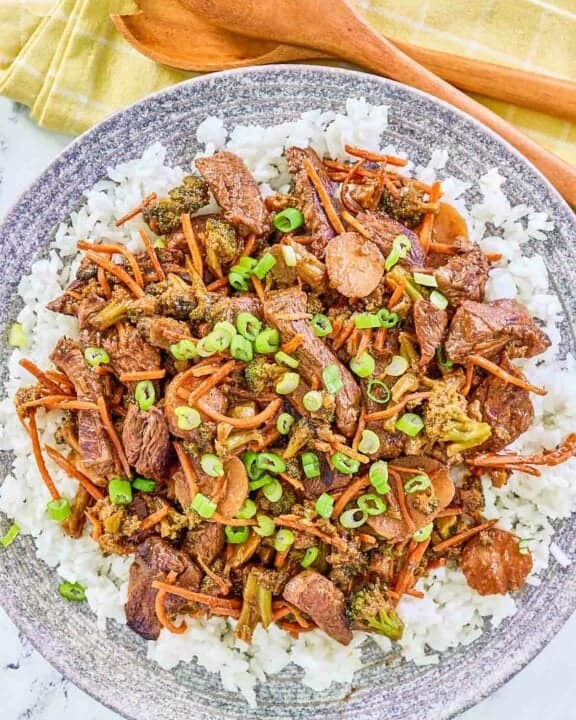 Overhead view of teriyaki beef stir fry over rice on a plate.