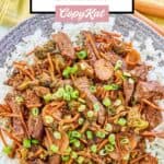 Overhead view of teriyaki beef stir fry over white rice on a grey plate.