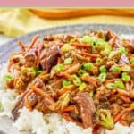 Teriyaki beef stir fry over rice on a grey plate.