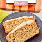 Overhead view of two slices of zucchini bread with cream cheese frosting on a black plate.