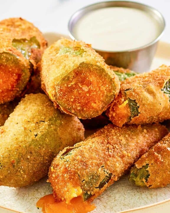Cheddar cheese jalapeno poppers and a cup of dipping sauce on a plate.