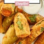 Overhead view of deep fried cheddar cheese jalapeno poppers and dipping sauce on a plate.