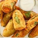 Overhead view of cheddar cheese jalapeno poppers and dipping sauce on a plate.