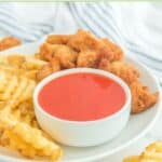 A bowl of homemade Chick Fil A Polynesian sauce, waffle fries, and chicken nuggets.