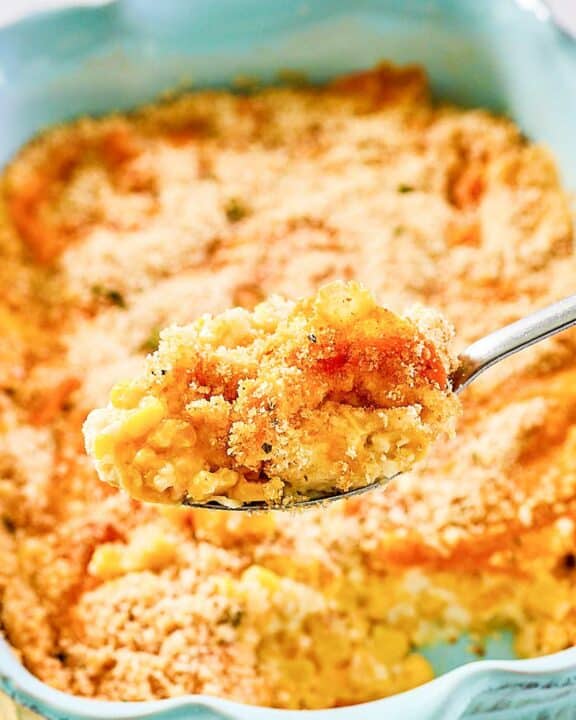 Creamed corn au gratin on a spoon and in a casserole dish.