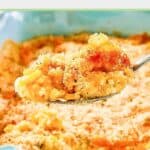 Creamed corn au gratin on a spoon held over the casserole.