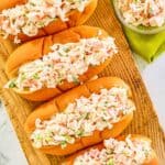 Overhead view of imitation crab salad in hoagie rolls and a small glass bowl.