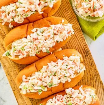 Overhead view of imitation crab salad in hoagie rolls and a small glass bowl.