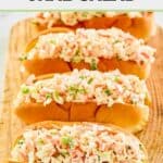 Homemade imitation crab salad in hoagie buns on a wood board.