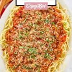 Overhead view of homemade spaghetti meat sauce over spaghetti pasta on a white platter.