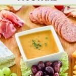 Homemade sweet hot mustard on a board with sliced meats, cheese, and olives.