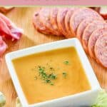 Homemade sweet hot mustard in a small bowl and sliced summer sausage.