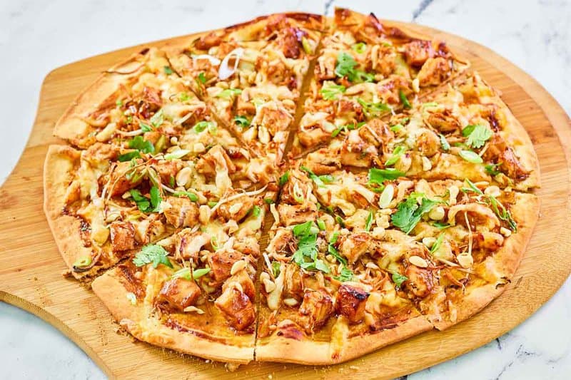 Copycat CPK Thai chicken pizza on a pizza peel.