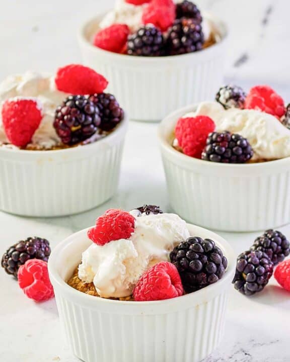 Copycat Brennan's oatmeal custard with whipped cream and berries in ramekins.