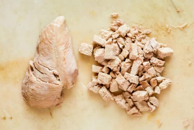 Two cooked chicken breasts whole and cut into pieces.