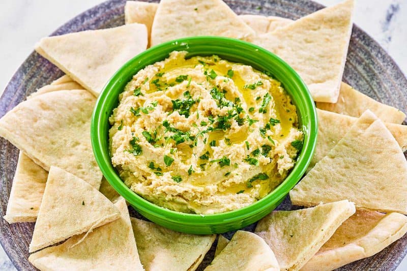 Creamy hummus and pita bread slices.