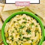Overhead view of creamy hummus and pita bread slices.
