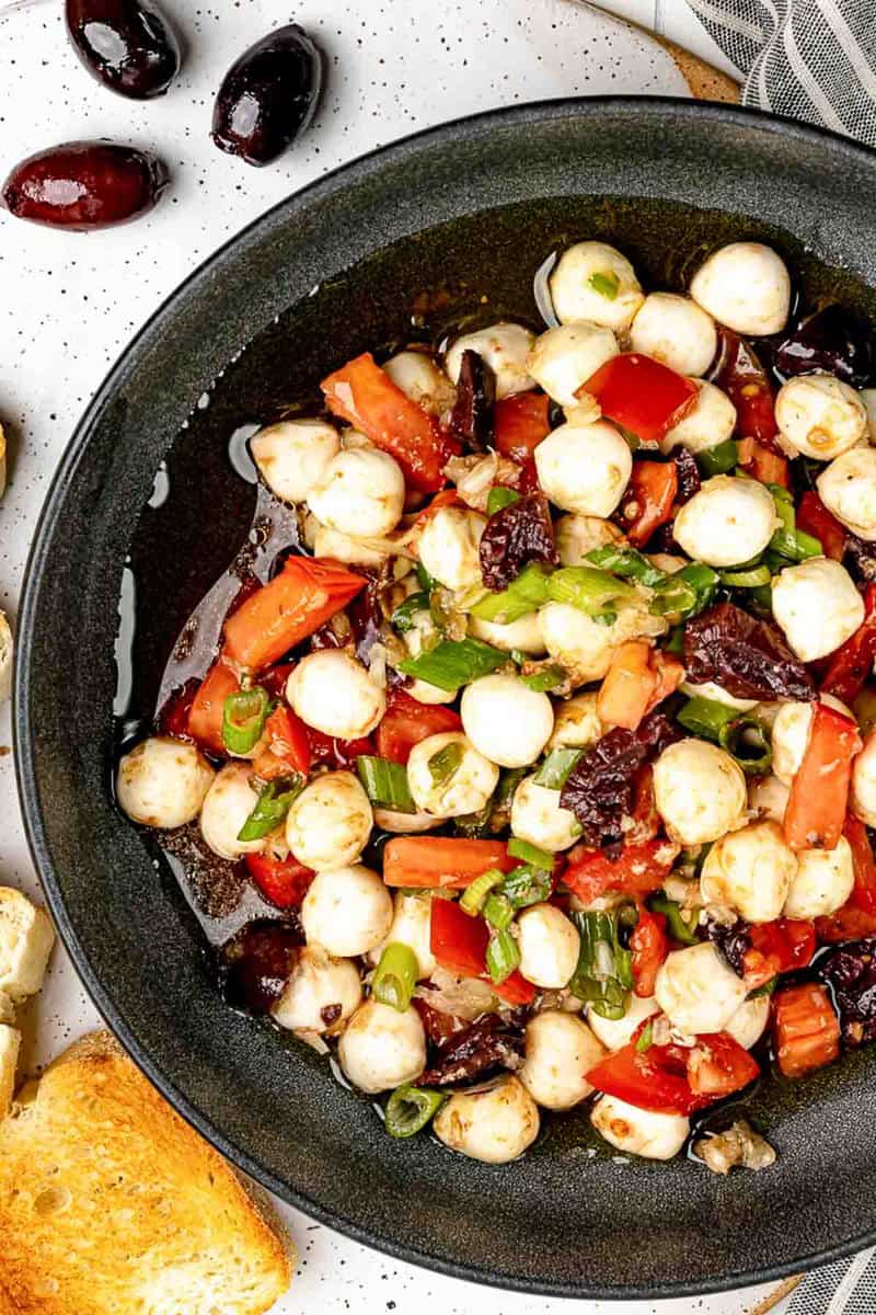 Closeup of homemade marinated mozzarella balls in a black bowl.