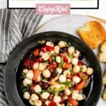Overhead view of marinated mozzarella balls in a black bowl and toasted bread.