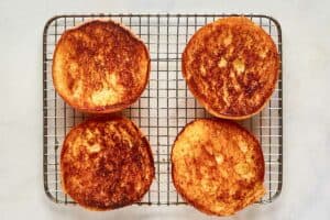 Toasted potato buns on a wire rack.