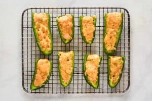 Buffalo chicken mixture inside jalapeno pepper halves.